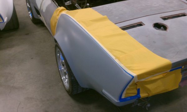 A 1968-1973 CORVETTE REAR FENDERS - 2" FLARE is being painted in a garage.