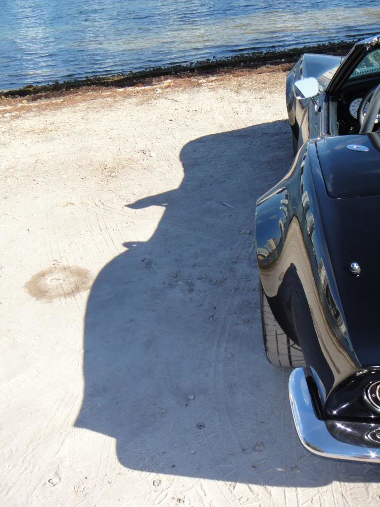 black corvette parked on beach with shadow