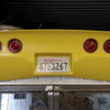 A yellow 1974-1982 REAR BUMPER - CHROME BUMPER LOOK tail light hangs from the ceiling of a garage.