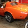 An orange corvette parked in a garage.