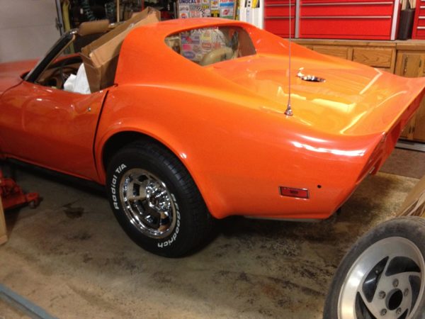 An orange corvette parked in a garage.