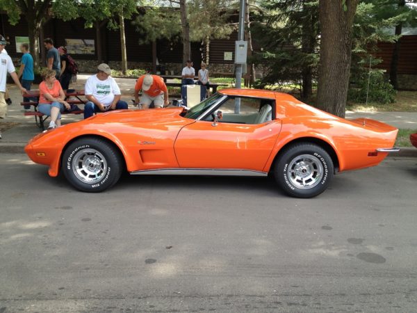 An orange corvette parked on a street.