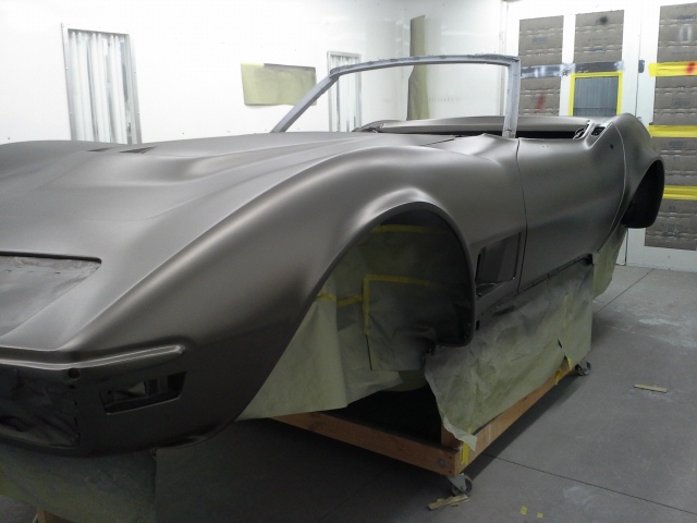 A chevrolet corvette is being painted in a garage.