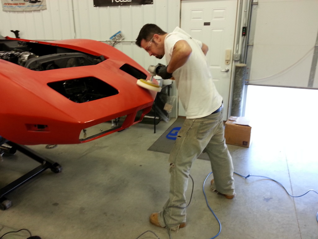 A man working on a red car in a garage.
