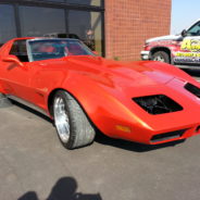 A red chevrolet corvette parked in front of a building.