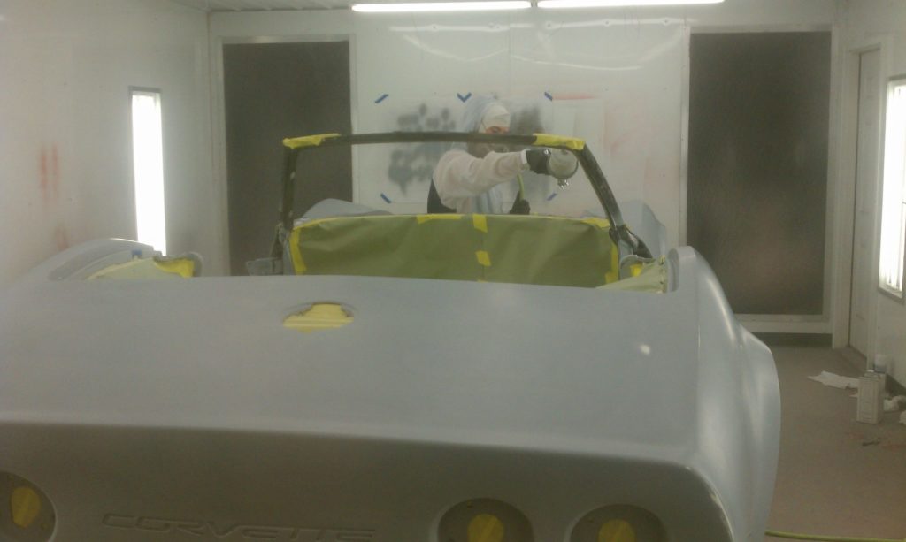 A man is painting a car in a garage.