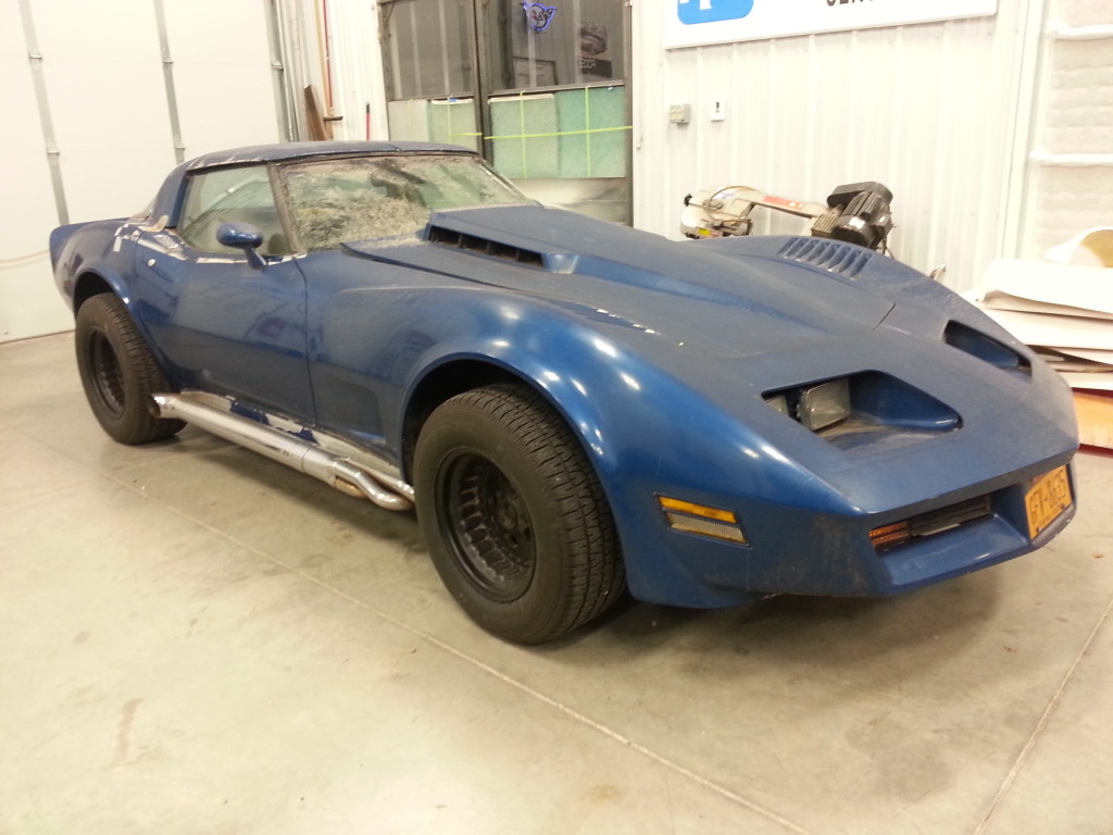A blue chevrolet corvette parked in a garage.