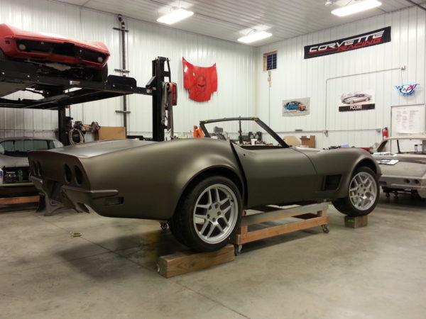 A brown corvette sitting in a garage.