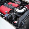 The engine compartment of a white car with red hoses would have LS1 SWAP AC BRACKETS FOR THE R4 COMPRESSOR.