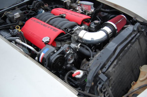 The engine compartment of a white car with red hoses would have LS1 SWAP AC BRACKETS FOR THE R4 COMPRESSOR.