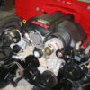 A red LS1 SWAP AC BRACKETS FOR THE R4 COMPRESSOR engine in a garage.