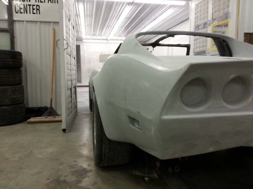 A white corvette sitting in a garage.