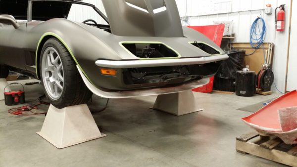 A 1968-1972 FRONT SPOILER - SS sitting on a lift in a garage.