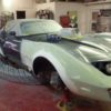 A 1980-1982 CORVETTE CHROME BUMPER CONVERSION KIT - 4" REAR 2" FRONT is being painted in a garage.