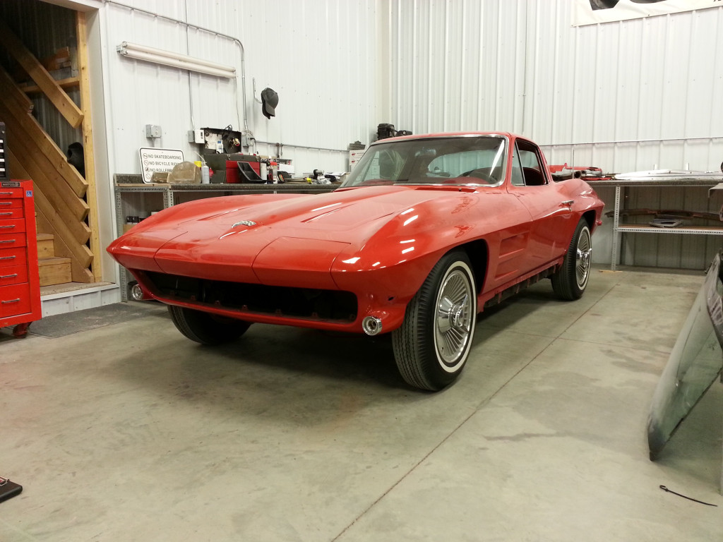 A red chevrolet corvette parked in a garage.