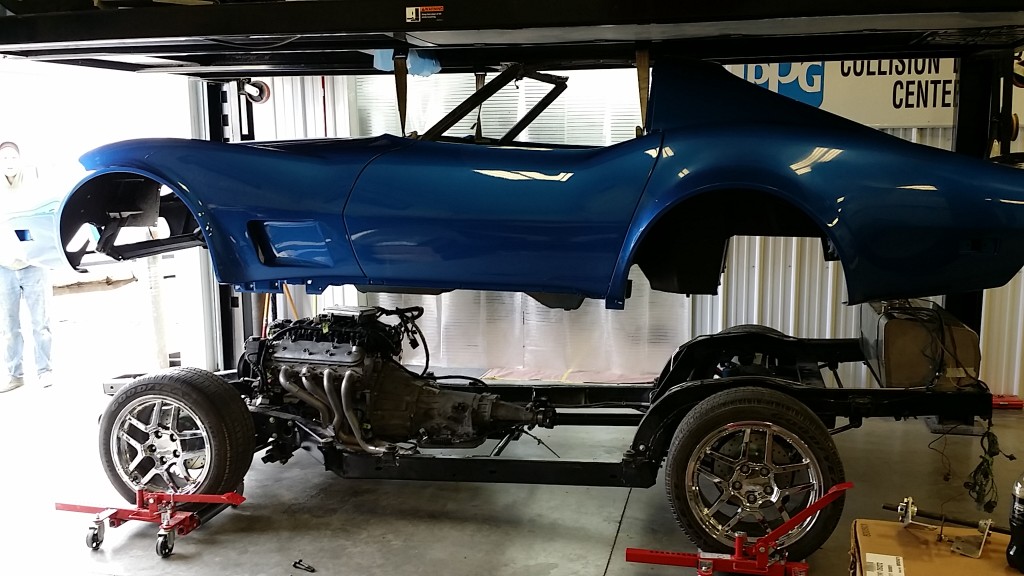 A blue corvette sitting on a lift in a garage.