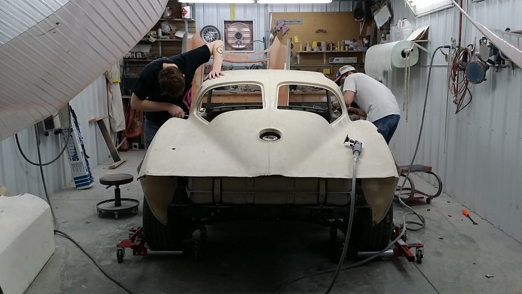 Two men working on a white car in a garage.