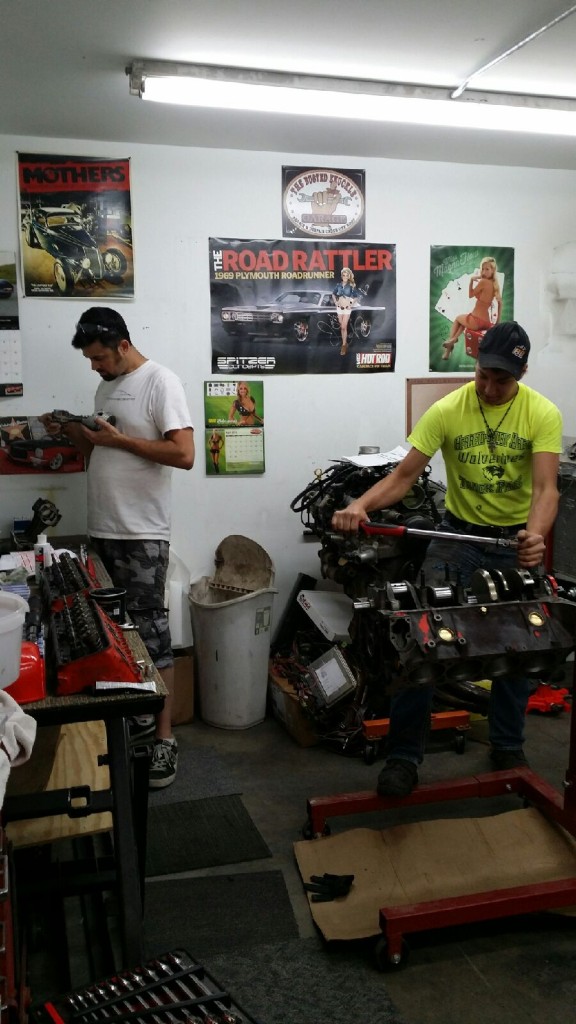 Two men working in a garage with a lot of equipment.