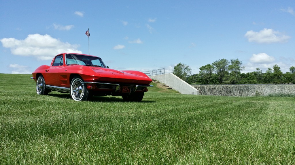 A red chevrolet corvette parked in the grass.