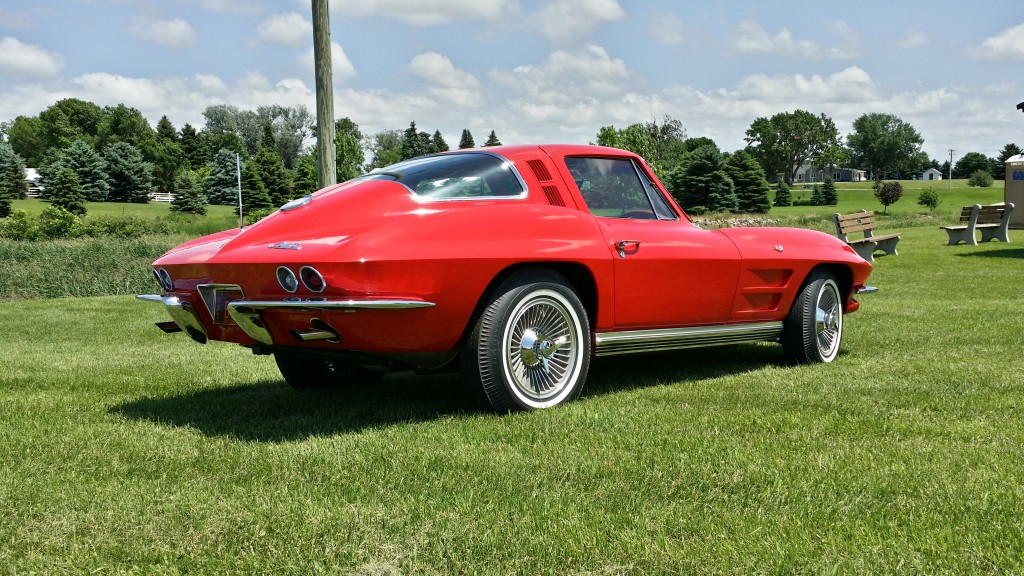 A red chevrolet corvette parked in a grassy field.