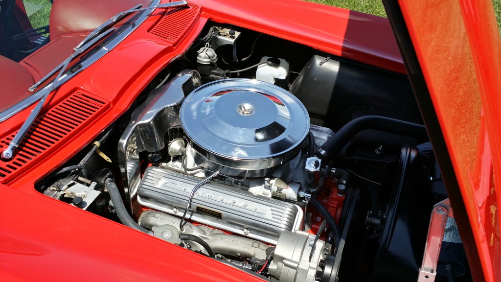 The engine compartment of a red car.