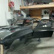 A 1967 Corvette Replica Roadster in a garage with a door open.