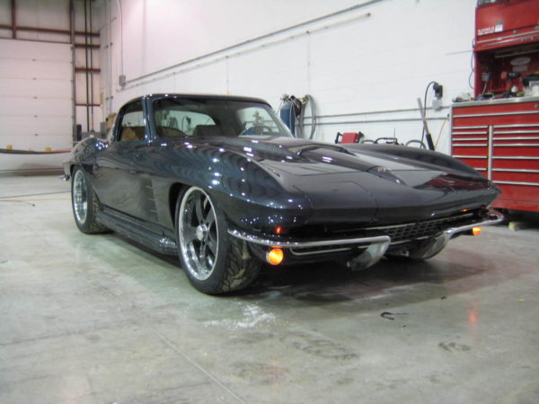 A black 1963-1967 Corvette Replica Coupe parked in a garage.