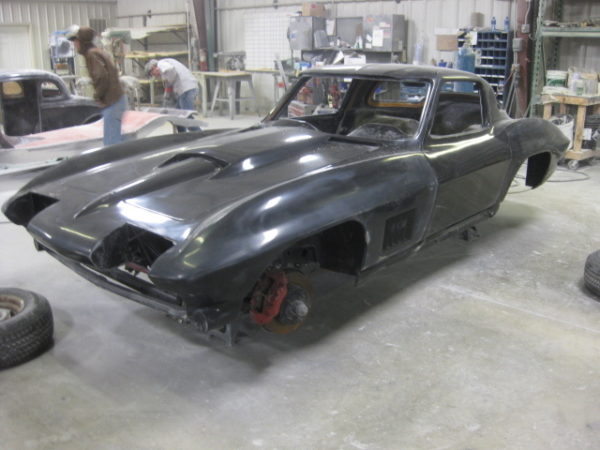 A 1963-1967 Corvette Replica Coupe is being worked on in a garage.