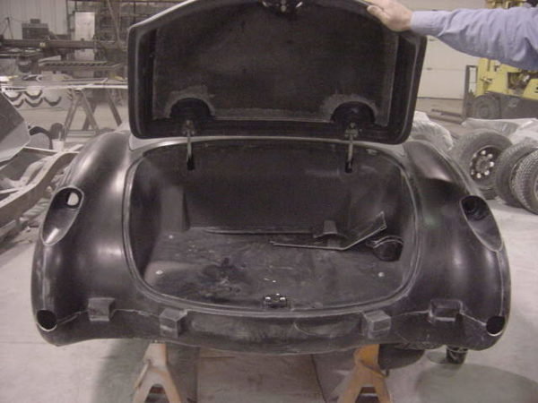 A black 1958-1960 Corvette Replica Body Kit with its trunk open in a factory.