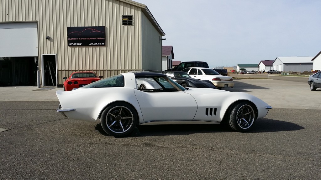A white corvette parked in front of a building.