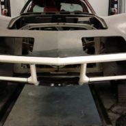 The front bumper of a car is being worked on in a garage.