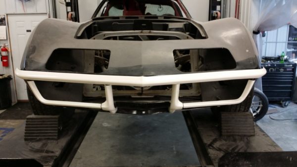 The front bumper of a car is being worked on in a garage.