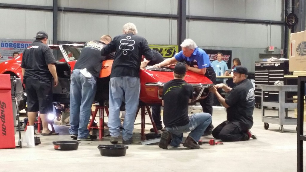 A group of men working on a car in a garage.