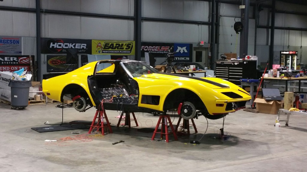 A yellow corvette sitting in a garage.