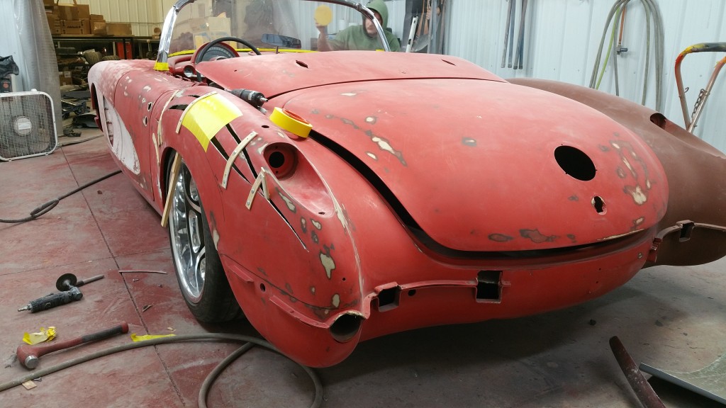 A red sports car is being worked on in a garage.