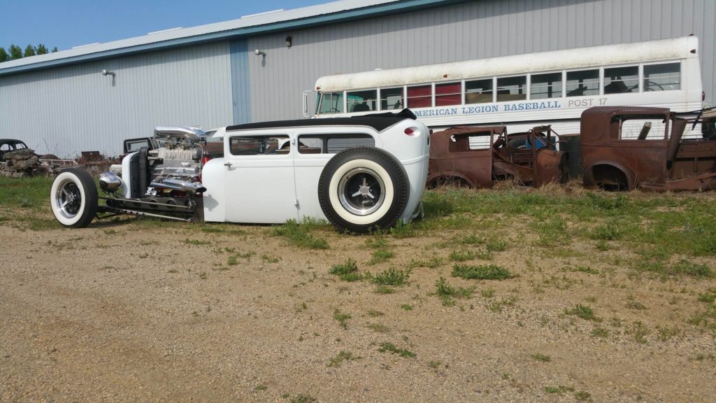 A white hot rod is parked in front of a building.