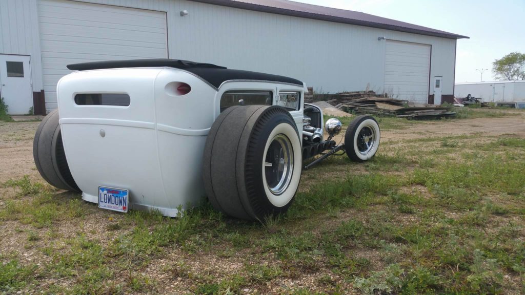 A white hot rod is parked in a field.