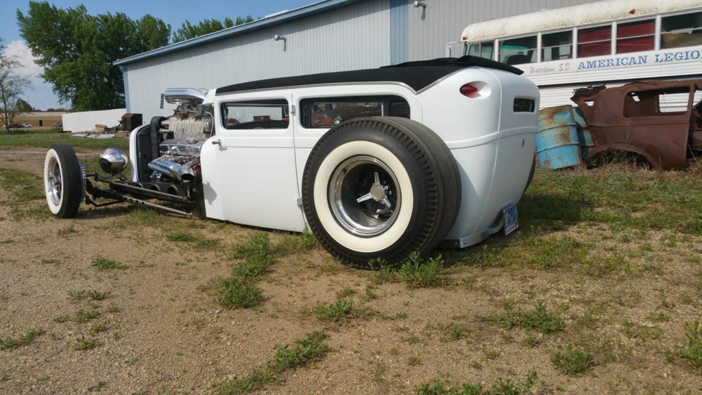 A white hot rod is parked in a field.