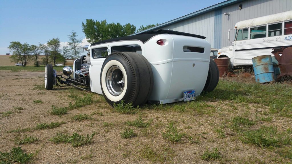 A white hot rod parked in a field.