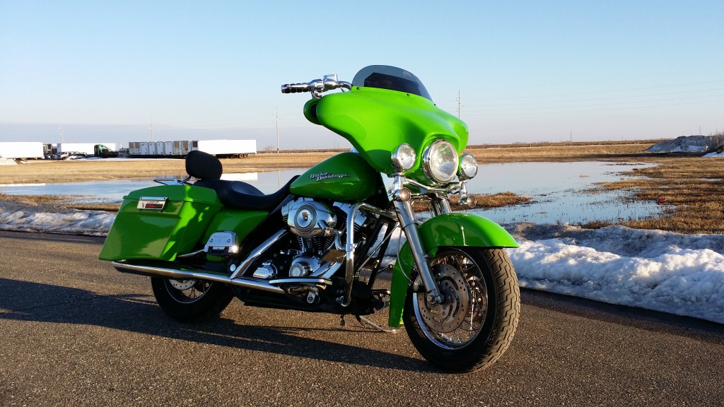 A green motorcycle parked on the side of the road.