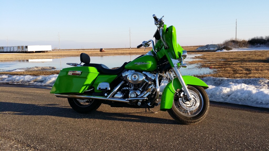 A green motorcycle parked on the side of a road.