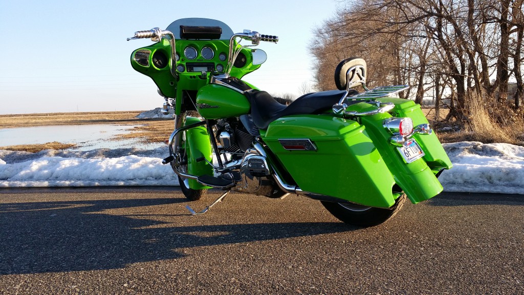A green motorcycle parked on the side of a road.
