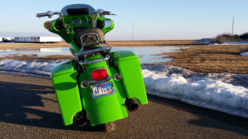 A green motorcycle parked on the side of the road.