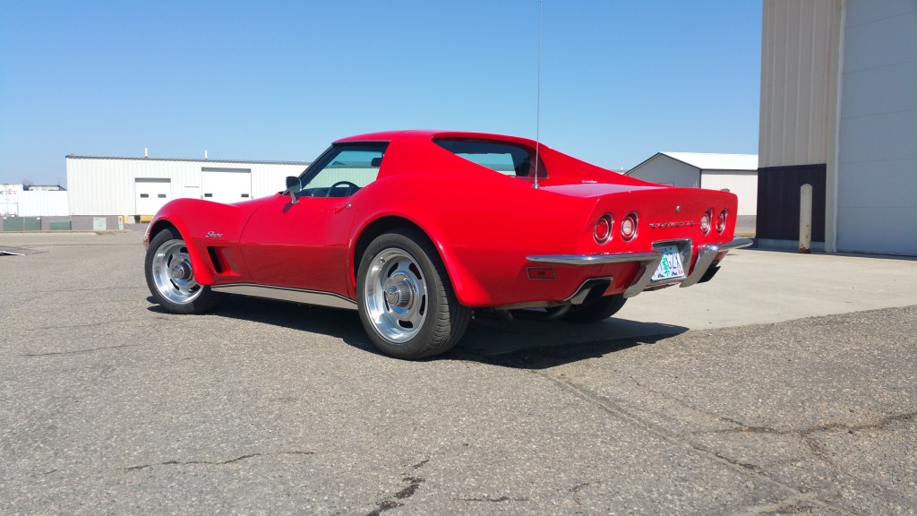 A red chevrolet corvette parked in front of a building.