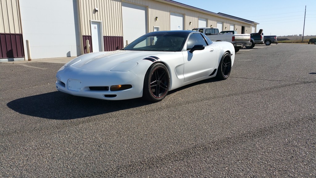 A white chevrolet corvette parked in a parking lot.