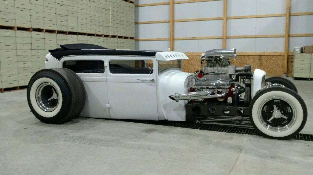 A white hot rod is parked in a garage.