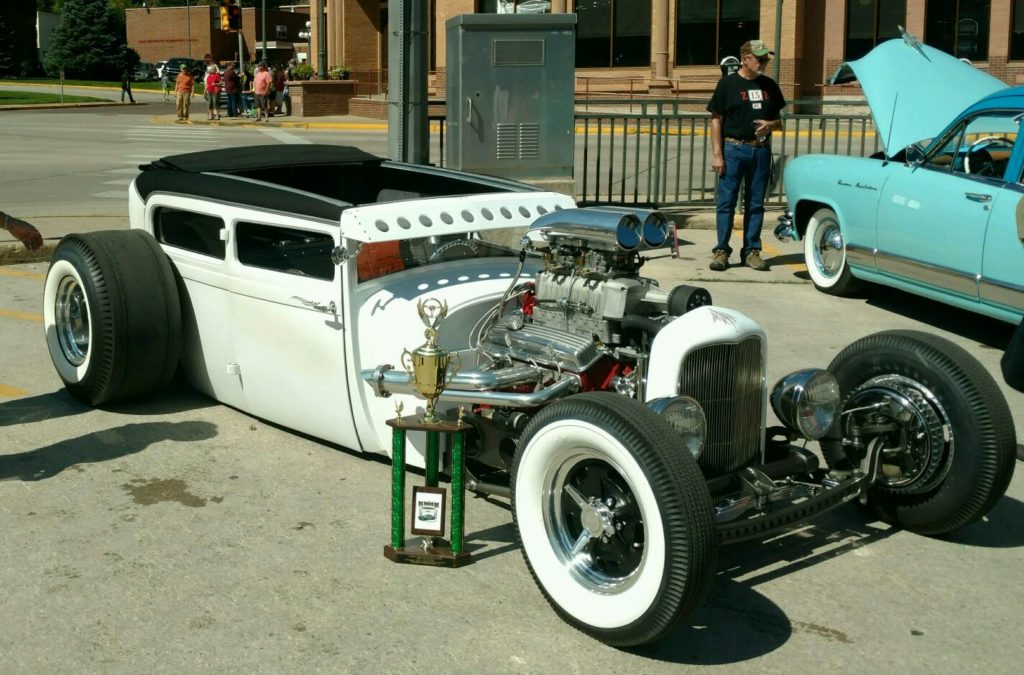 A white hot rod is parked in a parking lot.
