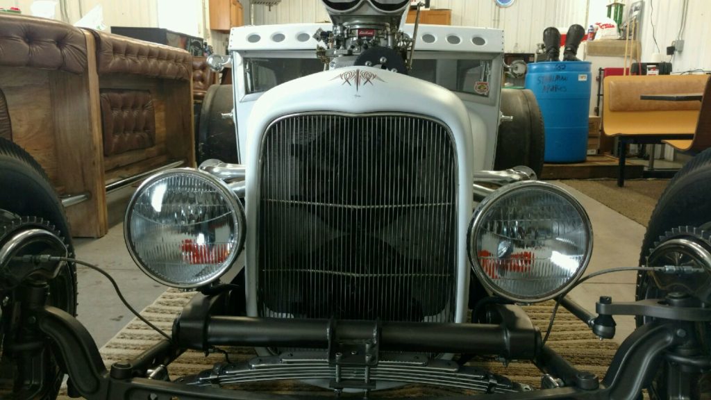 A white hot rod is sitting in a garage.