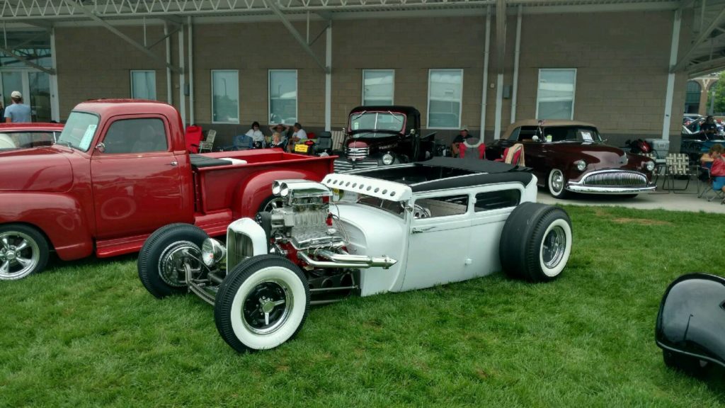 A group of antique cars and trucks are parked on the grass.