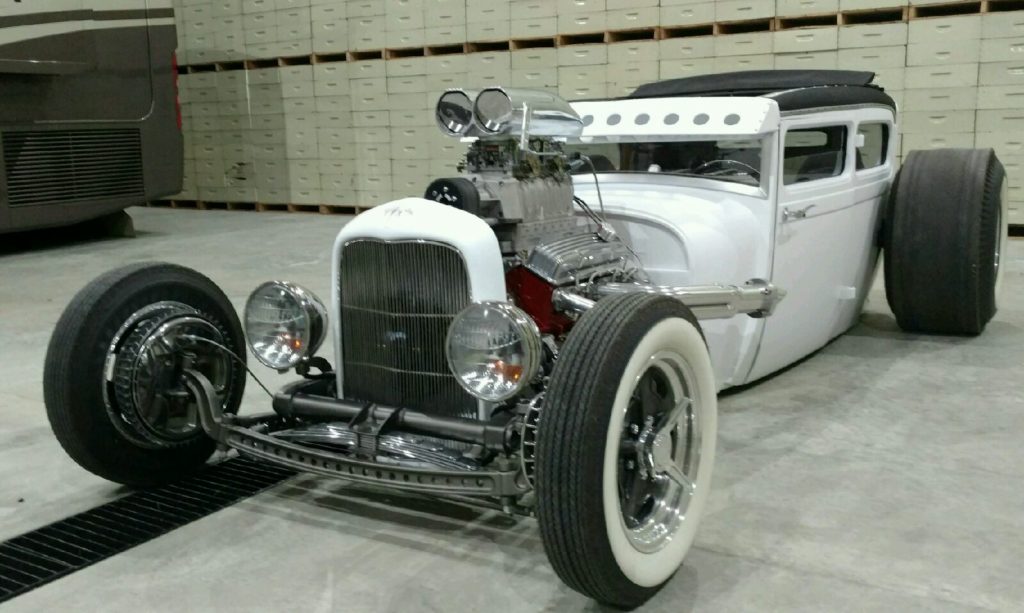A white hot rod is parked in a garage.